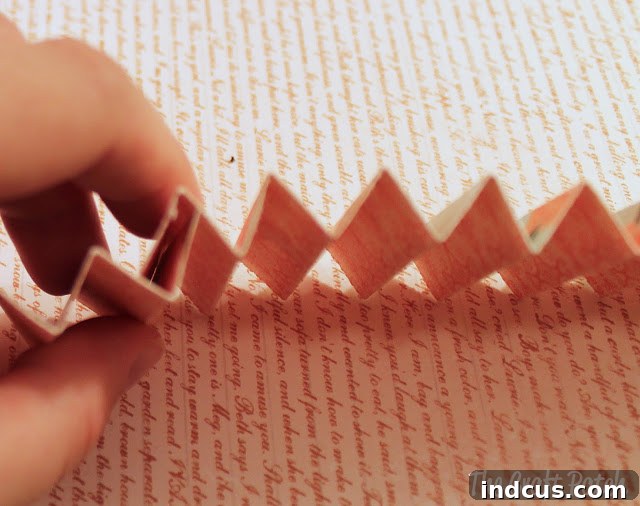 Gluing two accordion fold paper strips together to form a longer segment