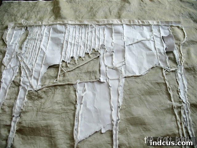 Demonstration of carefully tearing away the paper pattern from the back of the embroidered fabric after stitching is complete