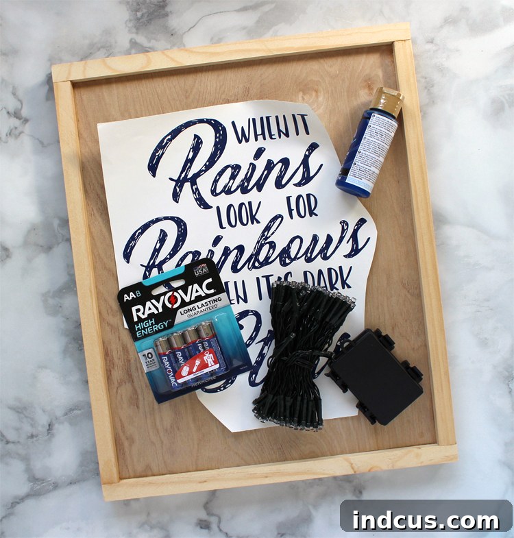 All the materials required to make a DIY farmhouse sign with vinyl lettering, including wood, paint, LED lights, and batteries.