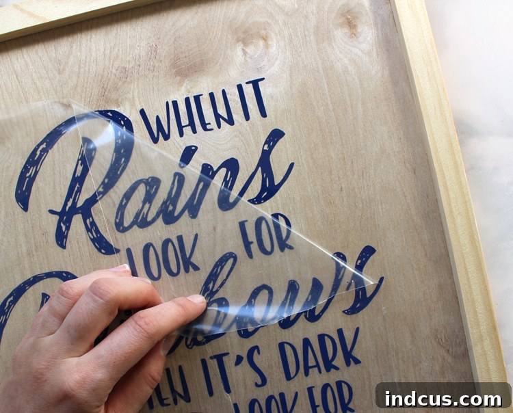 Close-up of a wooden sign with the vinyl quote 'When It Rains Look for Rainbows' applied, ready for light placement.