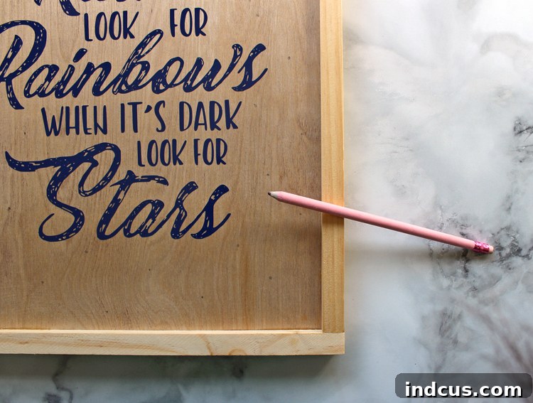 Wooden sign with a vinyl quote and pencil marks indicating where the LED lights will be drilled, preparing for the next step of the DIY project.