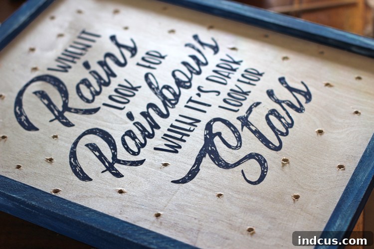 A farmhouse-style wooden sign with a decorative frame and drilled holes, ready for the insertion of twinkle lights.