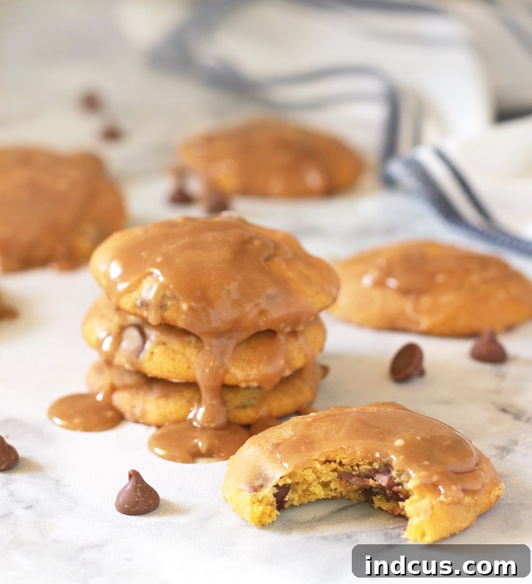 Pillowy soft pumpkin chocolate chip cookies with a glistening caramel glaze, ready to be enjoyed as a perfect fall treat.