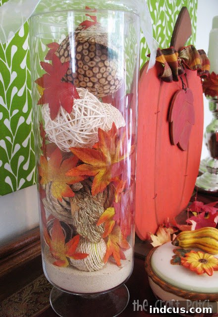 Cheap Chic Fall Decor 2 A beautifully arranged apothecary jar filled with rustic twig balls and vibrant faux fall leaves, showcasing budget-friendly Dollar Tree decor ideas.