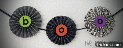 Embellished accordion paper flower banner with punched holes for ribbon