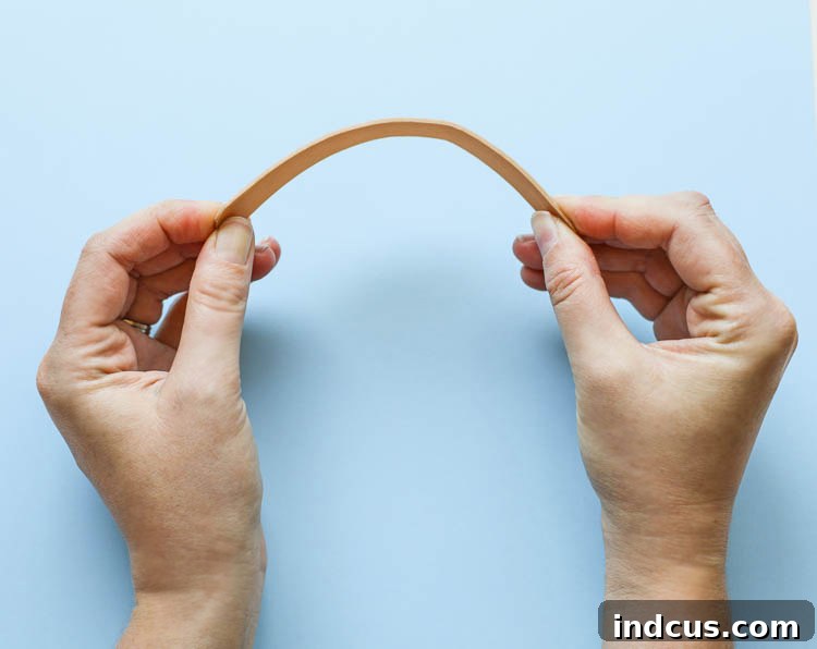 Hands gently bending a softened popsicle stick, demonstrating its pliability.
