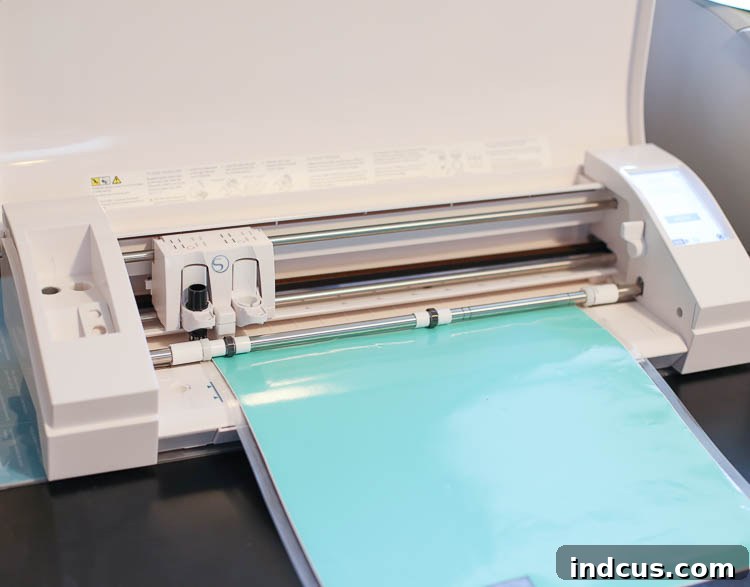 A Silhouette Cameo machine actively cutting a sheet of colored adhesive vinyl on a cutting mat, with the 'Lemonade' design visible on the vinyl surface.