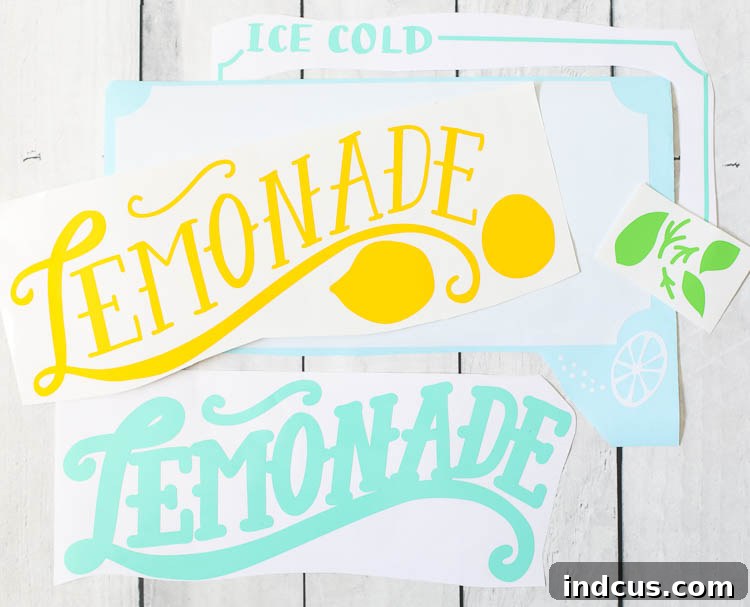 A close-up of a hand using a weeding tool to remove excess white adhesive vinyl from around a cut 'Lemonade' design, revealing the precise letterforms.