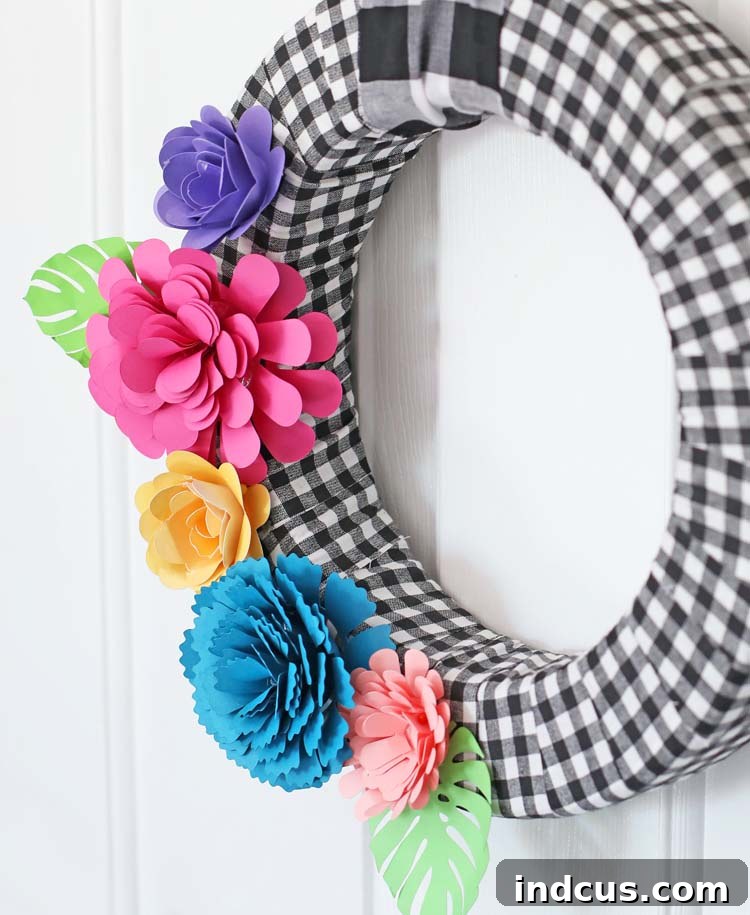 DIY wreath adorned with paper flowers and tropical leaves