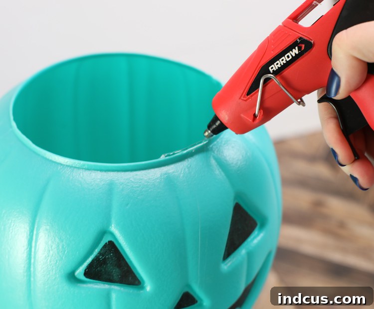 Gluing plastic pumpkin buckets together with a strong adhesive for a topiary
