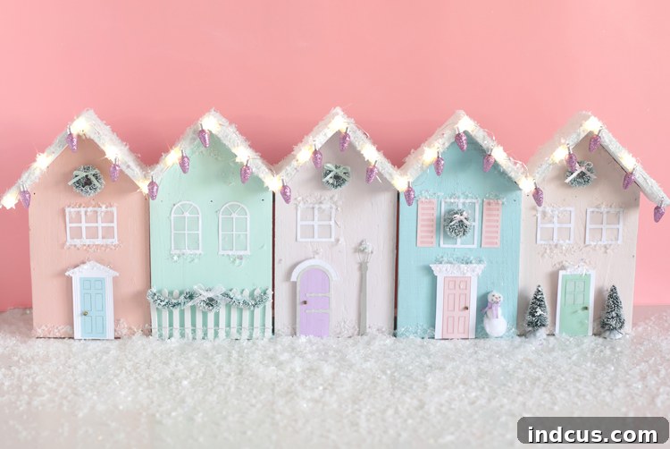 Collection of miniature Christmas row houses illuminated with festive lights, adding a cozy glow to holiday decor.