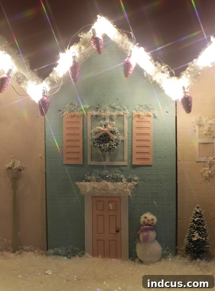 A close-up of a miniature Christmas house row, beautifully lit up with fairy lights, showcasing its festive and cozy appeal.