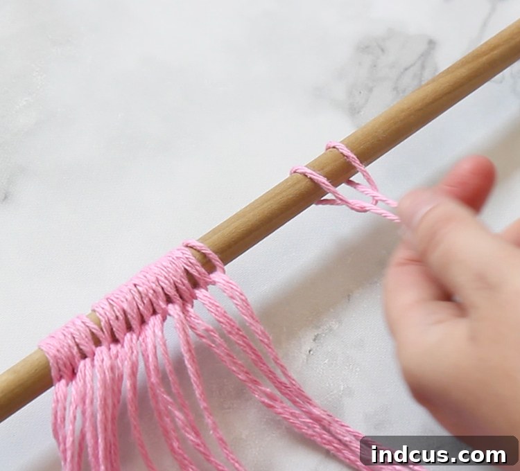 How to tie the basic macrame knot, illustrating the Lark's Head Knot for attaching yarn to a dowel in simple macrame projects.
