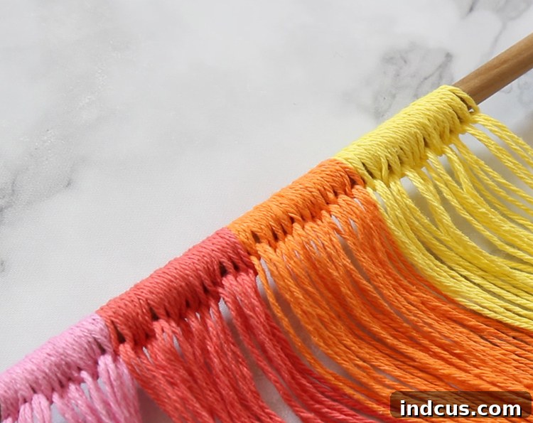 How to attach yarn to the dowel using basic macrame techniques, demonstrating the first steps of a DIY wall hanging.