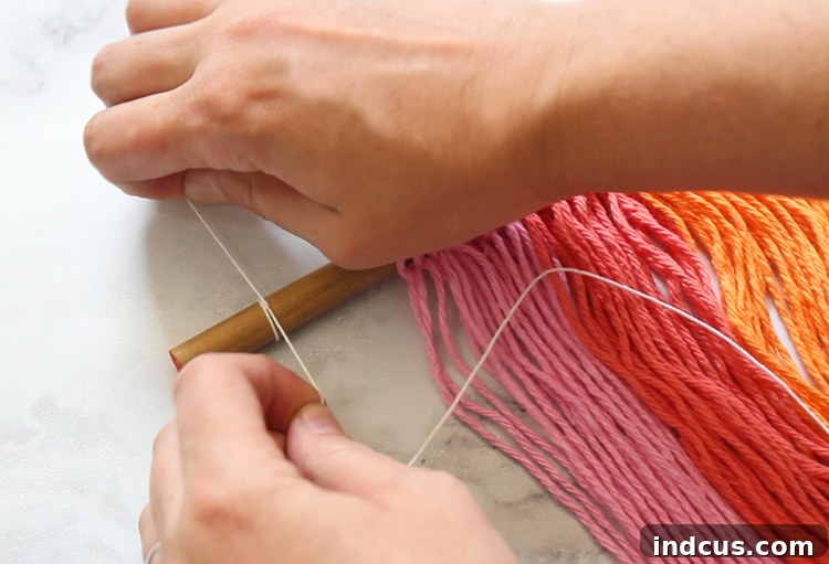 Easy rainbow craft using yarn and paper, showing the final step of adding a hanging string to the macrame for display.