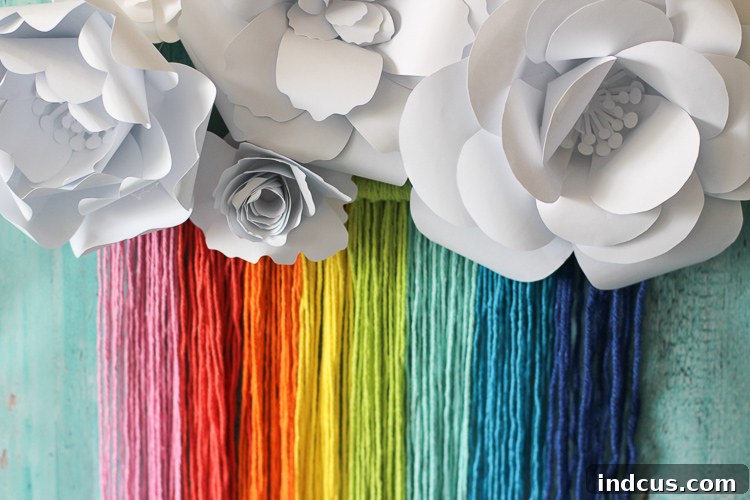 Boho rainbow wall hanging, now adorned with handmade paper flowers, creating a whimsical and unique piece of decor.