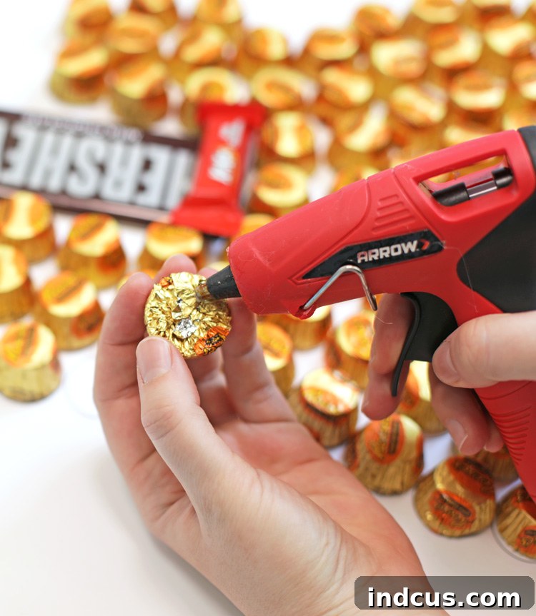 Close-up of Reese's Peanut Butter Cups being hot glued onto the guitar template on foam core