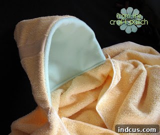 Soft, custom-made hooded bath towel with adorable animal ears, designed for a baby or toddler, lying flat on a surface, ready for use after bath time
