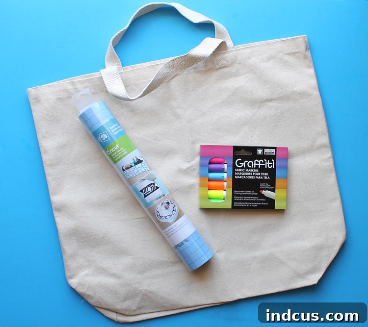 Crafting supplies laid out: a blank canvas tote bag, various neon fabric markers, and stencil vinyl, ready for a DIY project.