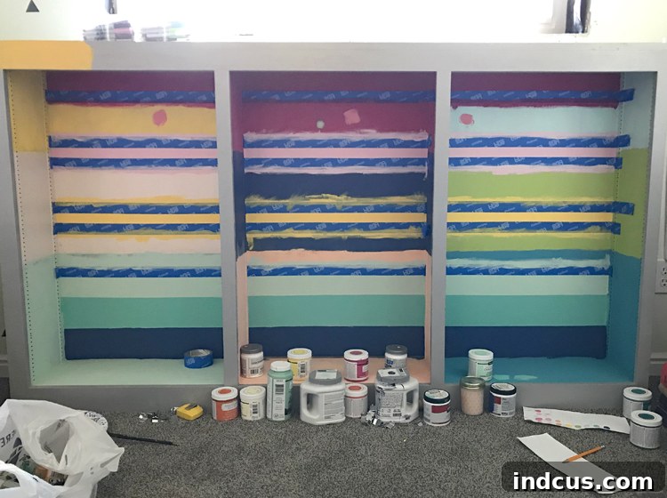 Detailed view of rainbow stripes being taped and painted on the cabinet, showcasing the process