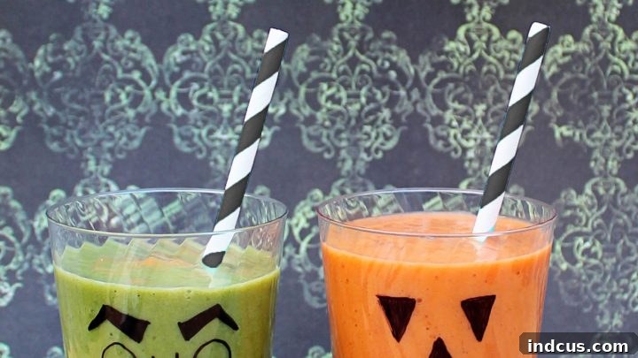 Colorful Halloween smoothies with spooky faces drawn on the glasses.