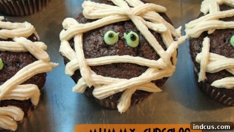 Mummy cupcakes decorated with white frosting and candy eyes.