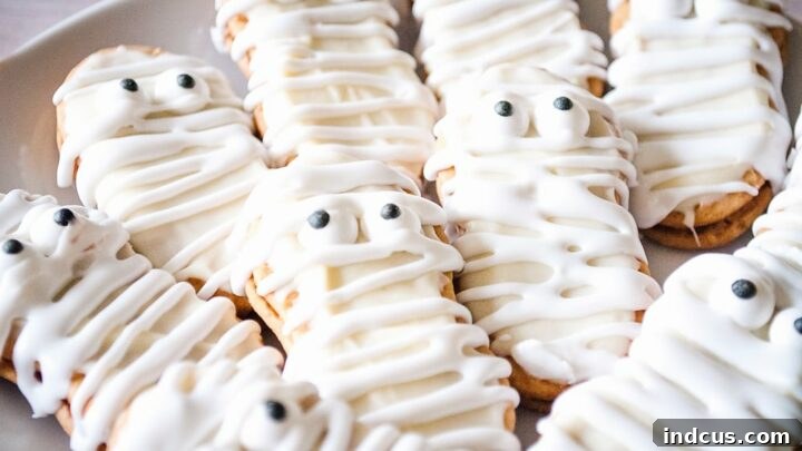 Halloween mummy Nutter Butter cookies decorated with white icing and candy eyes.
