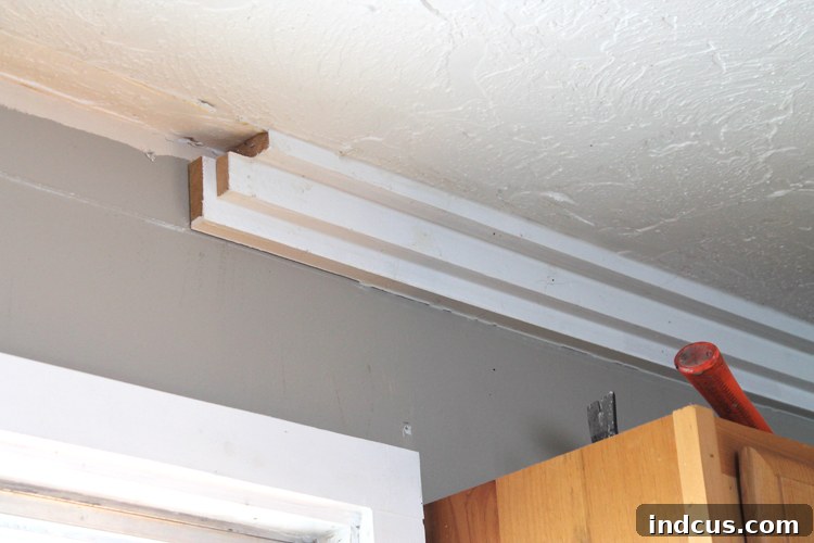 Close-up of old, damaged crown molding being removed from a ceiling and wall