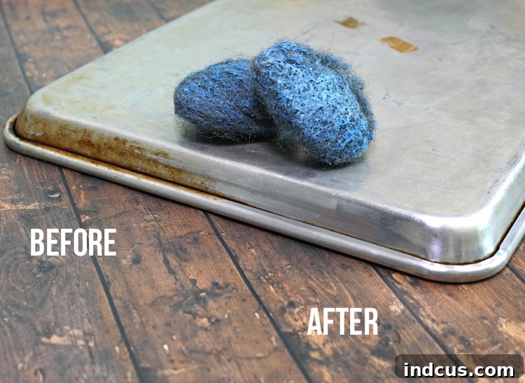 Close-up of a cookie sheet being scrubbed with an SOS pad to remove baked-on grime.