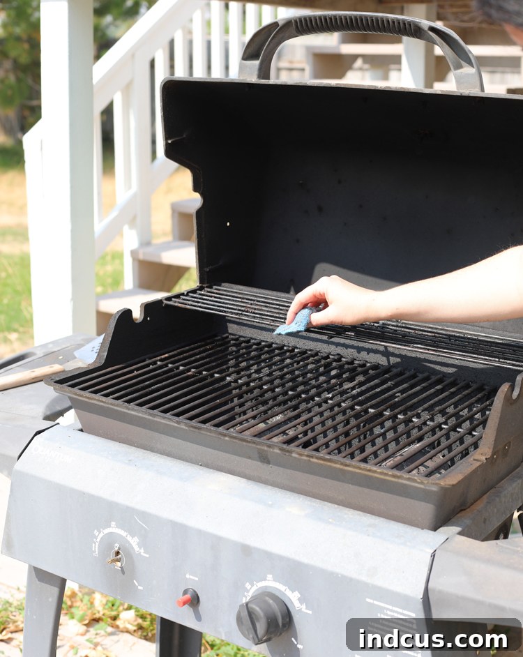 An SOS pad being used to clean charred residue off a barbecue grill grate.