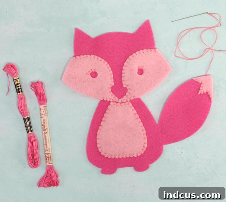 Hand stitching internal felt layers for a stuffed animal, showing embroidery detail