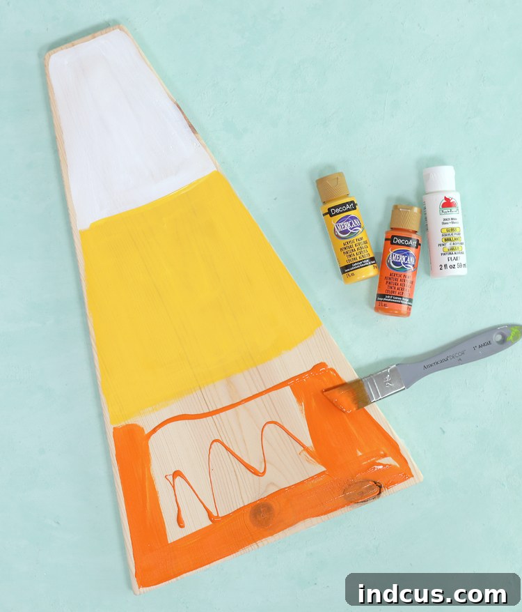 Painting a candy corn design on one side of the wood