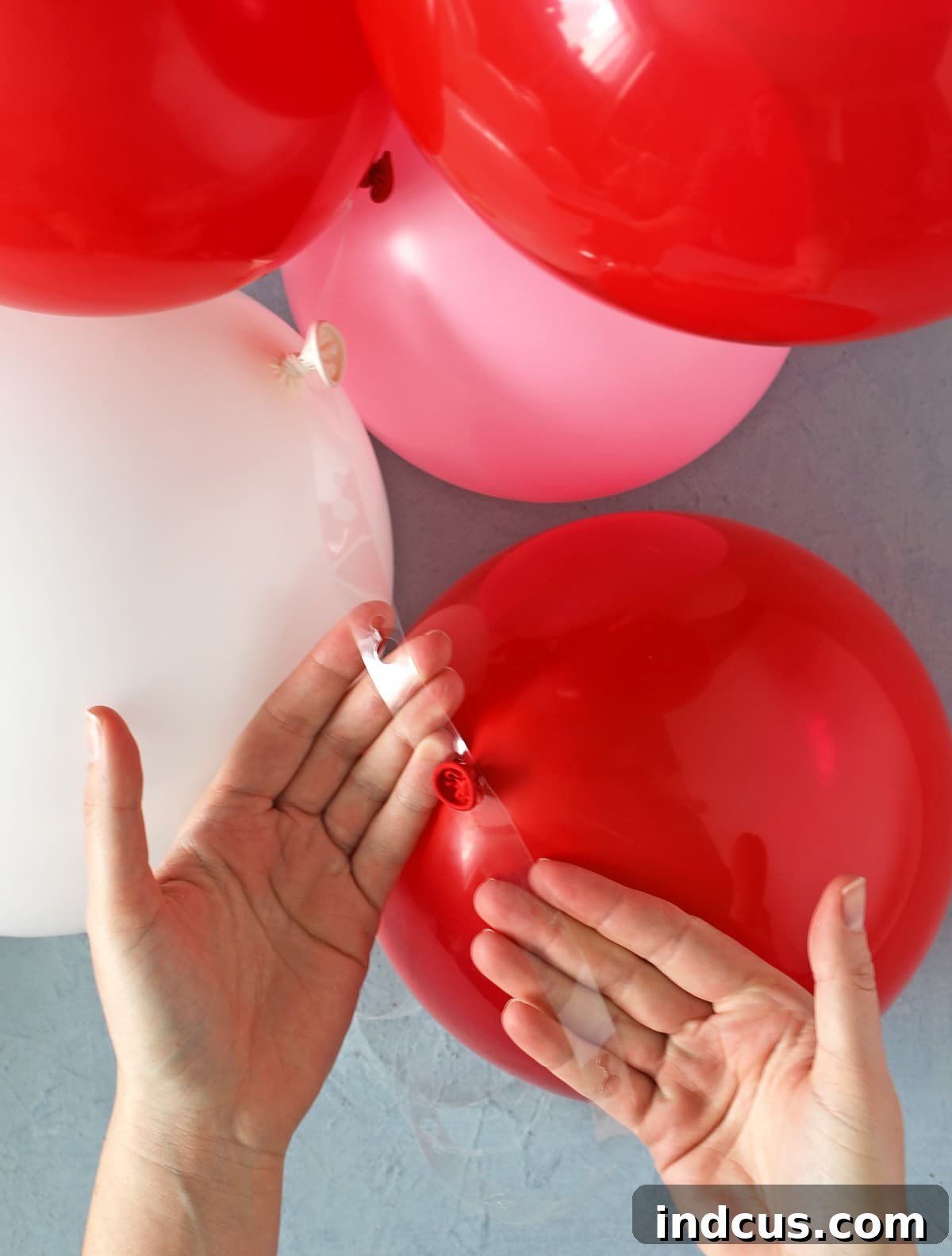 A close-up showing how to use a clear plastic balloon strip to create a garland.